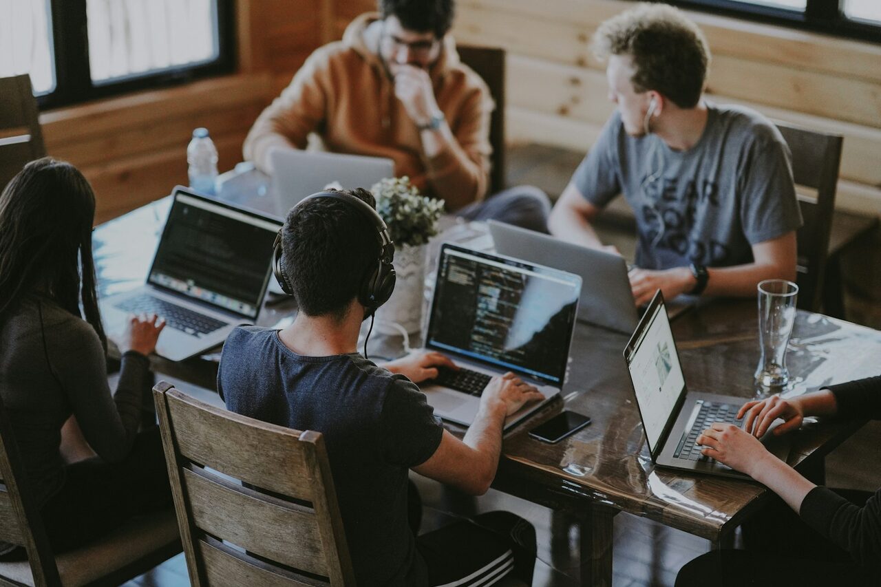 A B2B software go-to-market team collaborating on laptops and dashboards in a modern office